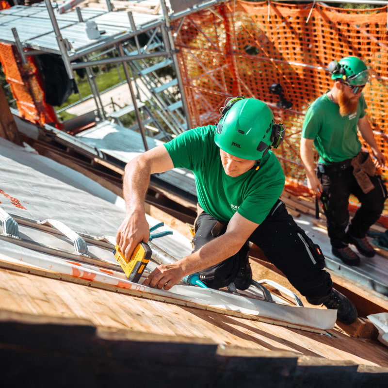 Lernender Zimmermann bei der Arbeit mit Holz